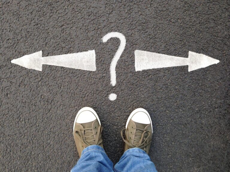 feet standing on street with road markings. question mark between arrows pointing left or right