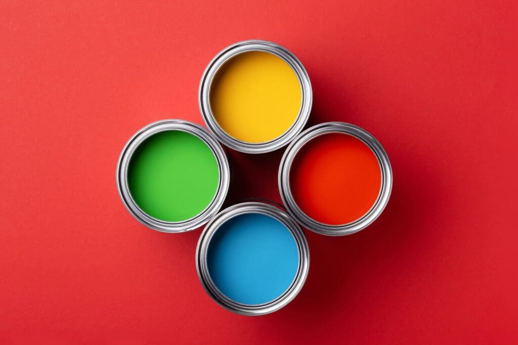 Four Cans of Colorful Paint on Red Background.