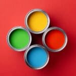 Four Cans of Colorful Paint on Red Background.