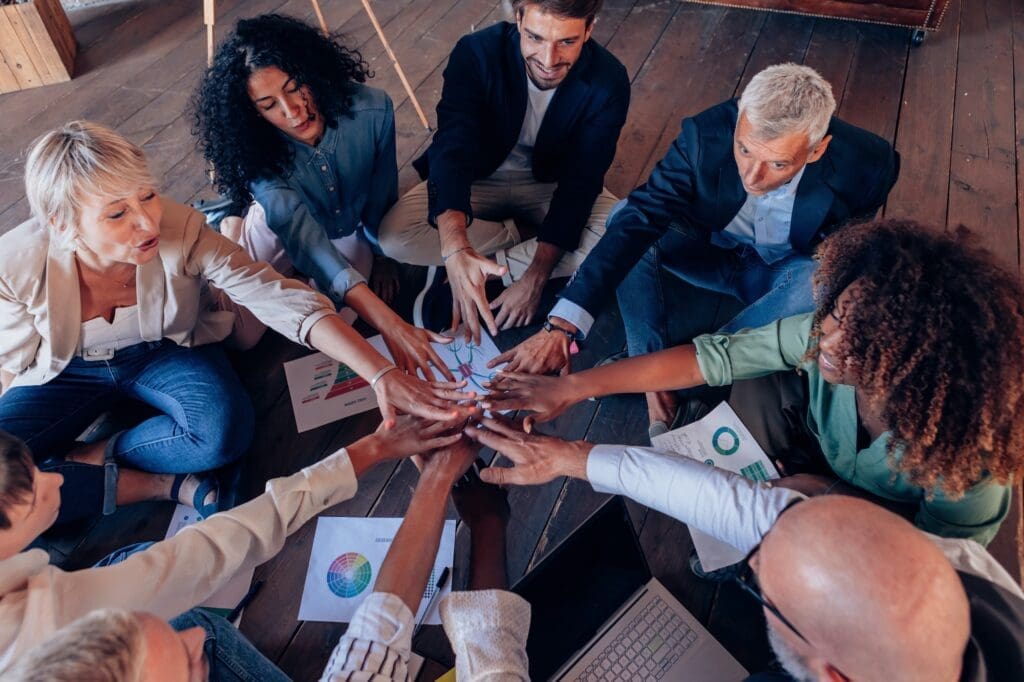 group of people working in team sitting on circle on floor with positive vibes