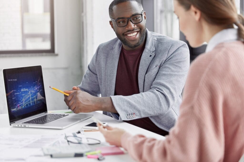 Smiling male manager rejoices great success of his company, presents information to fem