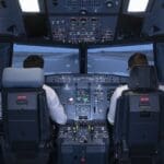 Two pilots in the cockpit of a commercial flight simulator preparing to start the flight