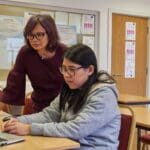 a woman showing a woman something on the laptop