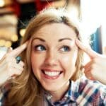 Young smiling positive thinking successful woman pointing finger to her head.