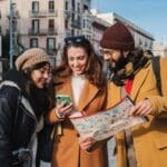 Group of tourist people sightseeing and searching a location on a map and on a smartphone app on a