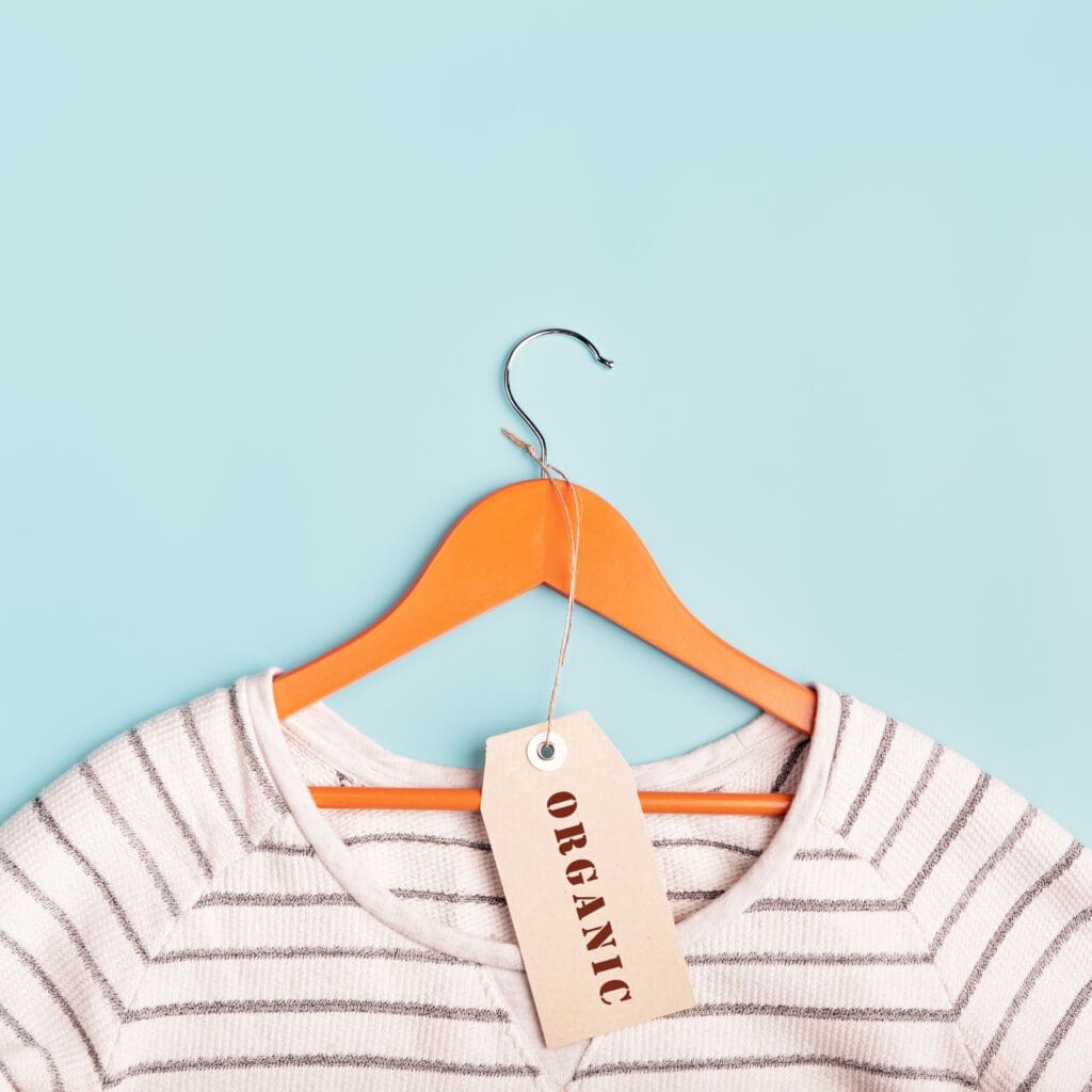 White striped sweatshirt on a hanger and tag with inscription Organic. Eco-friendly clothing