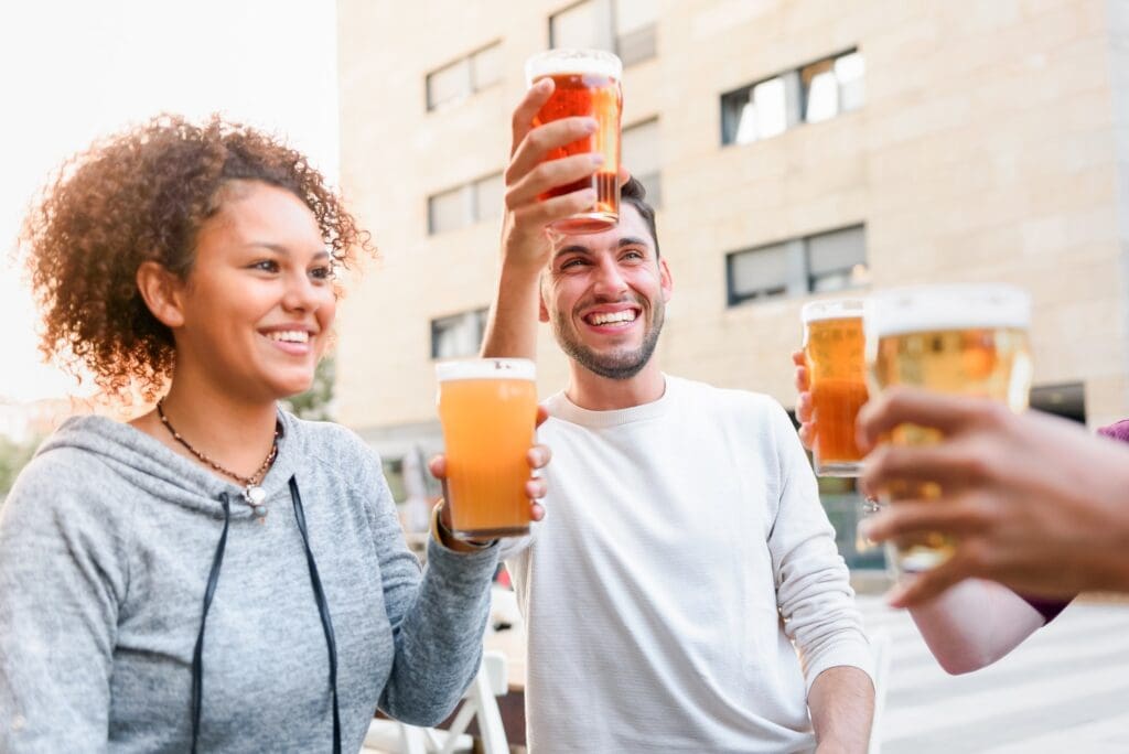 Cheerful friends with no disputes cheering with beer in cafe