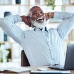 Happy black man stretching at desk for relax, online success and work life balance on office laptop