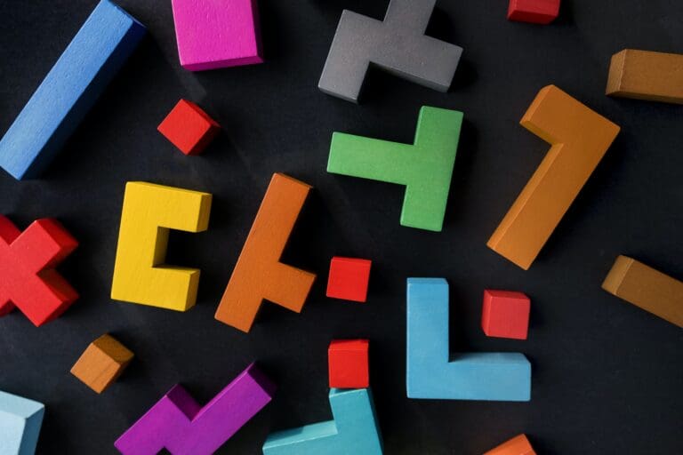Different colorful shapes wooden blocks on black background, flat lay.