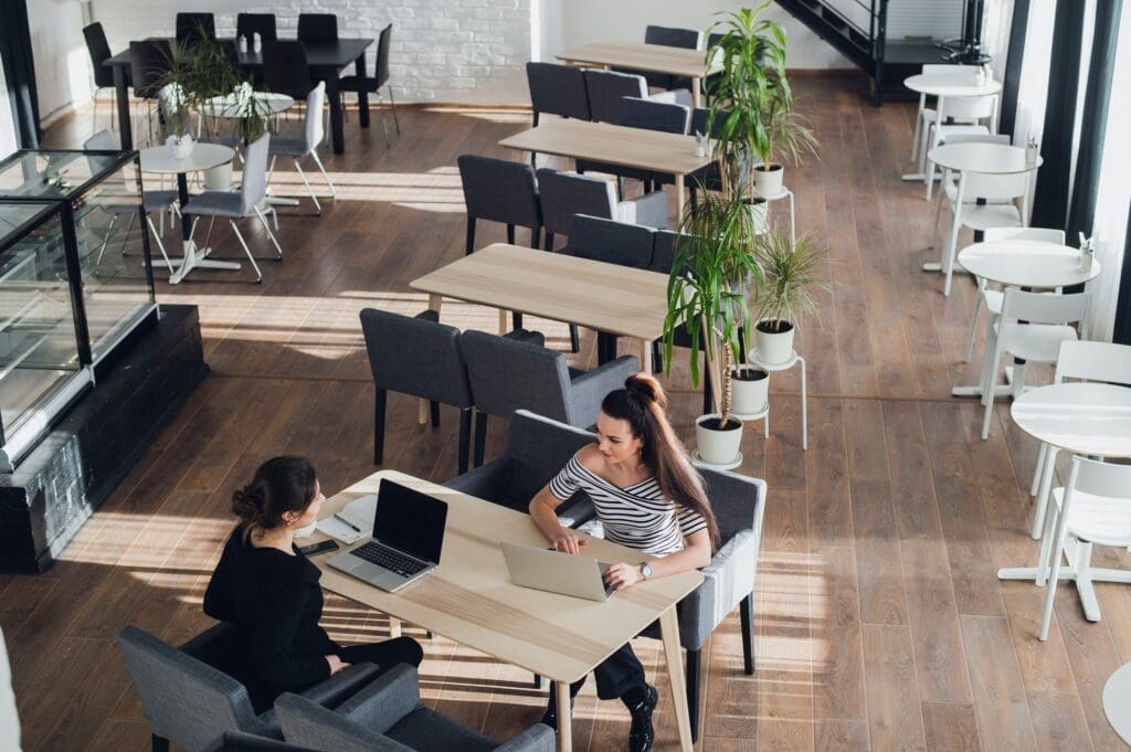 One-on-one meeting.Two young business women sitting at table in cafe. Girl shows colleague