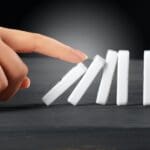 Woman hand toppling dominoes. Chain reaction business concept