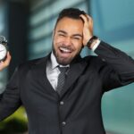 Black businessman with alarm clock. Time management concept