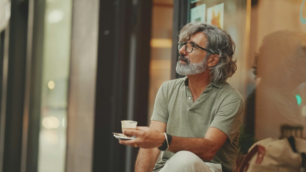 Mature gentleman in eyeglasses drinks aroma coffee hiring older workers and age diversity
