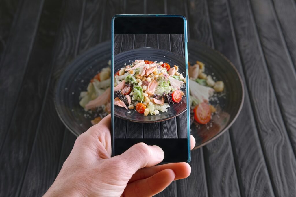 Photographing salad with smoked salmon with mobile phone. Food blogging. Low-Cost Marketing Strategies and User Generated Content. Tag images with Long-Tail Keywords