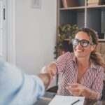 Smiling caucasian female hr manager handshake hire male candidate at job interview