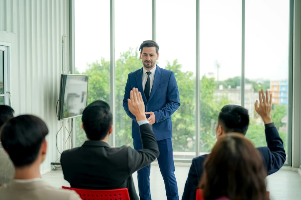 Raised up hands of large group in seminar class room to agree with speaker at conference seminar