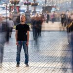 The man stands on the crowded street. Male loneliness