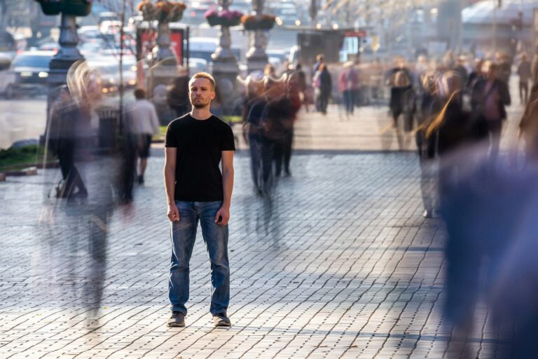 The man stands on the crowded street. Male loneliness