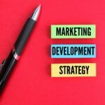 colored pen and paper with the words marketing, development and strategy.