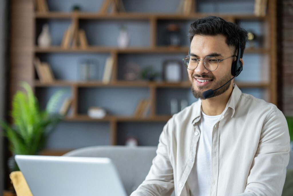 Smiling remote customer service representative working remotely with headset and laptop