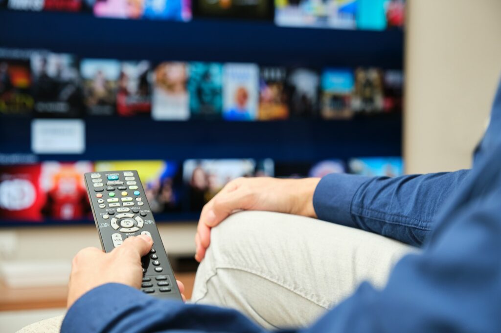 unrecognizable man sitting on the sofa looking on the tv for content on a streaming platform automatic content recognition