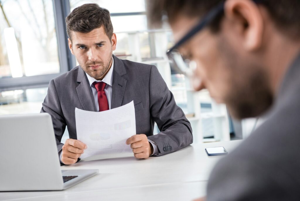 unsatisfied boss looking at upset colleague at business meeting