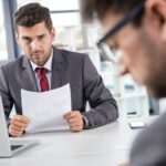 unsatisfied boss looking at upset colleague at business meeting