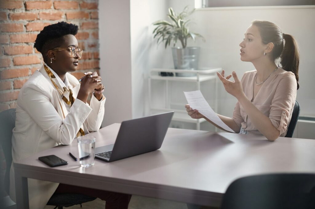 Young woman communicating with human resource manager while applying for job in the office.