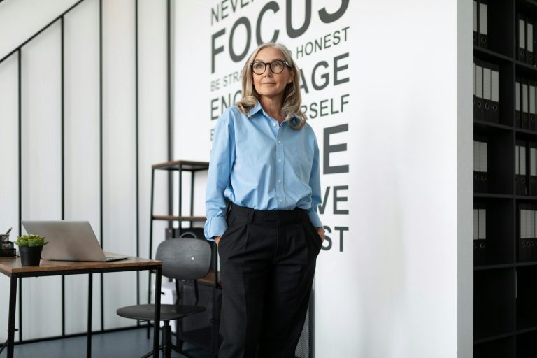 Business woman executive in a blue shirt stands in the middle of the office and looks into the