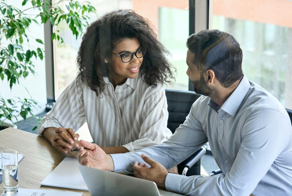 Female smiling trainee listening to ceo mentor leader at office meeting.