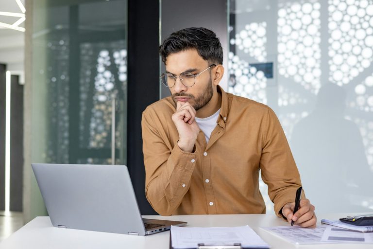 Focused businessman working on laptop in modern office environment