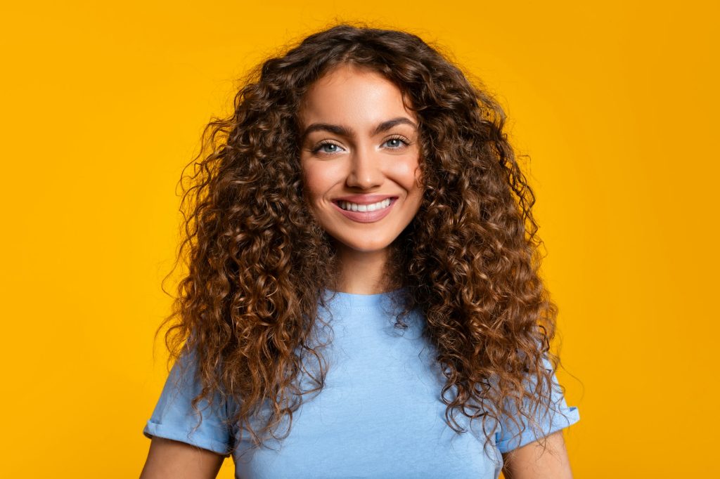 Friendly smiling woman with blue shirt on yellow