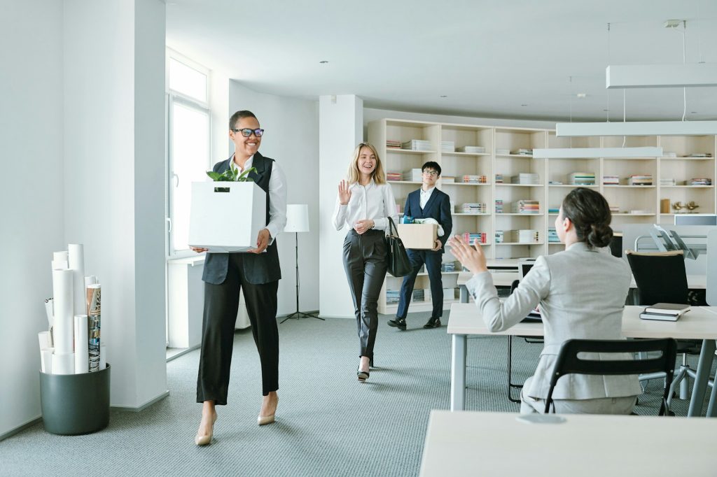 Group of young happy colleagues with boxes returning to work