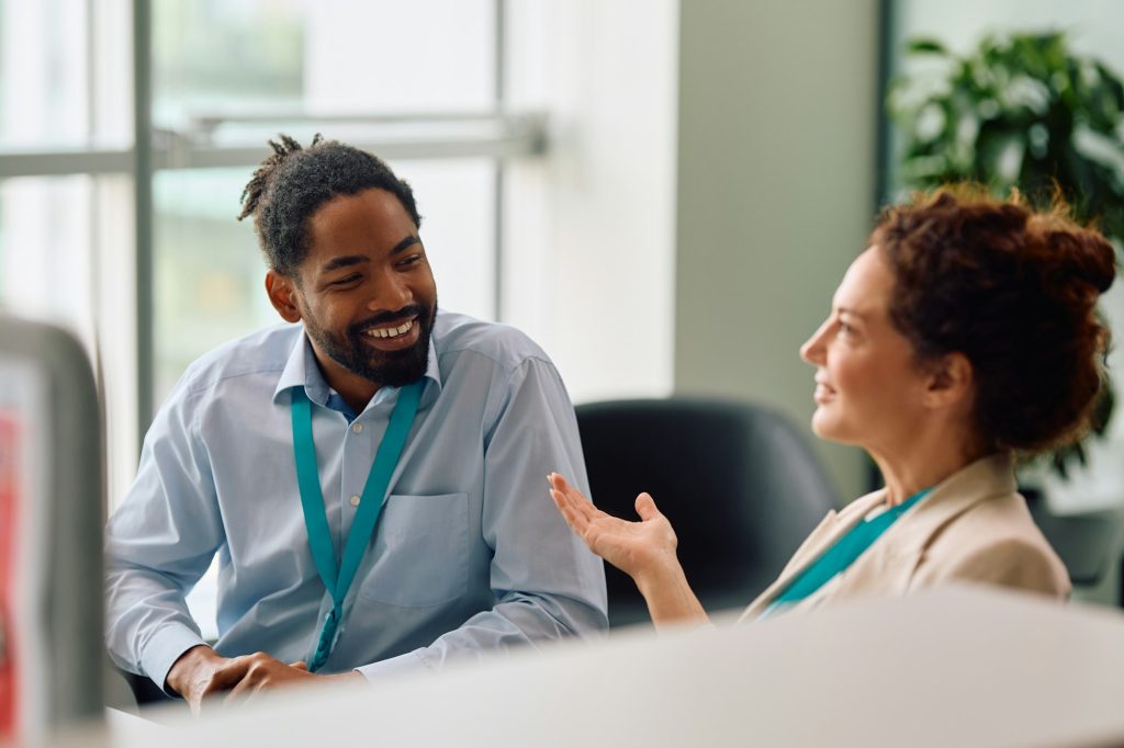 Social situation. Happy businessman talking to female colleague while working at corporate office.