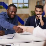 Happy young businessman shaking hand of female doctor