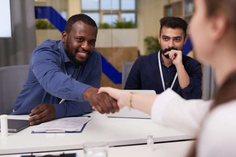 Happy young businessman shaking hand of female doctor