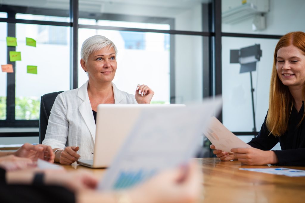 Female manager with laptop listening empathetically to corporate meeting.