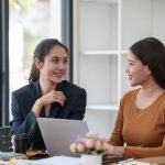 Two asian businesswomen discussing and reviewing documents in office.