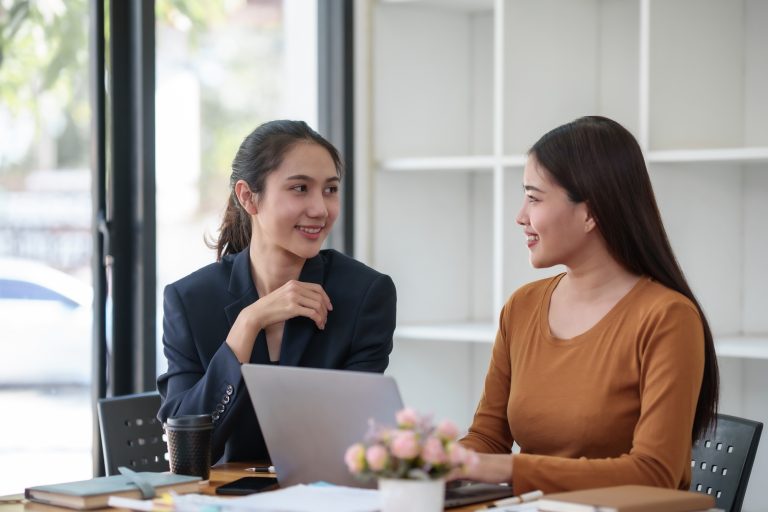 Two asian businesswomen discussing and reviewing documents in office.