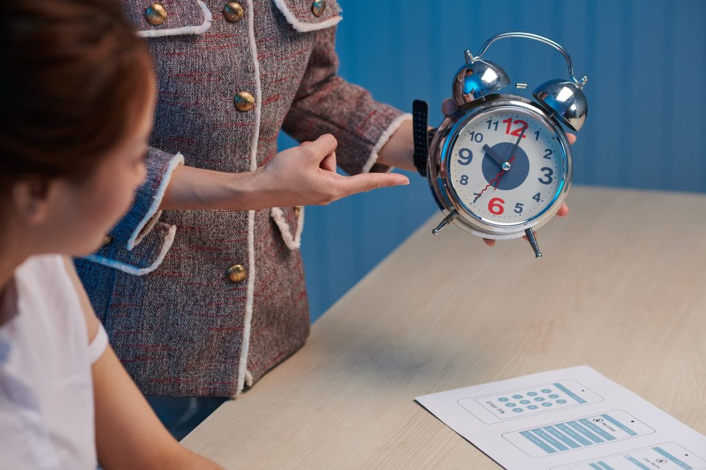 Boss showing alarm clock to designer