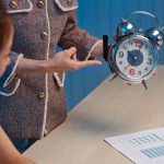 Boss showing alarm clock to designer