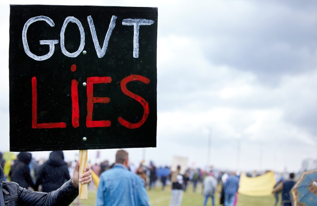 Unrecognisable demonstrators holding up signs and protesting against government corruption