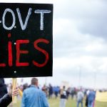 Unrecognisable demonstrators holding up signs and protesting against government corruption