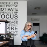 self-sufficient and self-confident businesswoman holding a phone in her hands in the office
