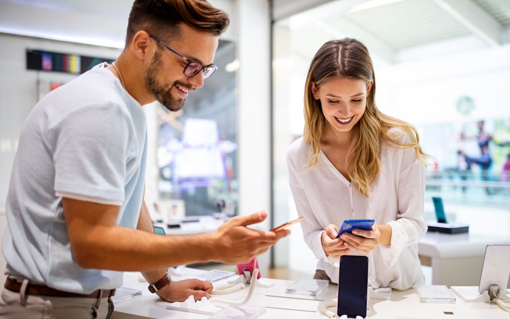 Shopping a new digital device. Happy couple buying a smartphone in store.