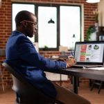 African american person using laptop to work on business charts and financial growth