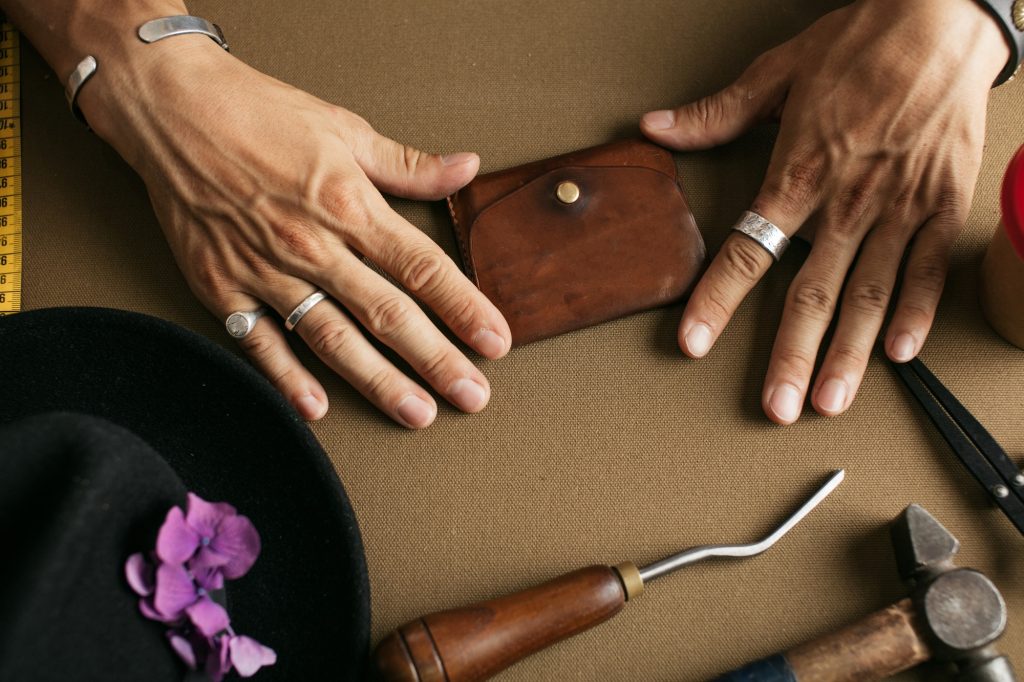 Leather goods master and handmade leather wallets. Workflow in the workshop.