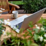 Top view of laptop on table on balcony in summer, outdoors office concept