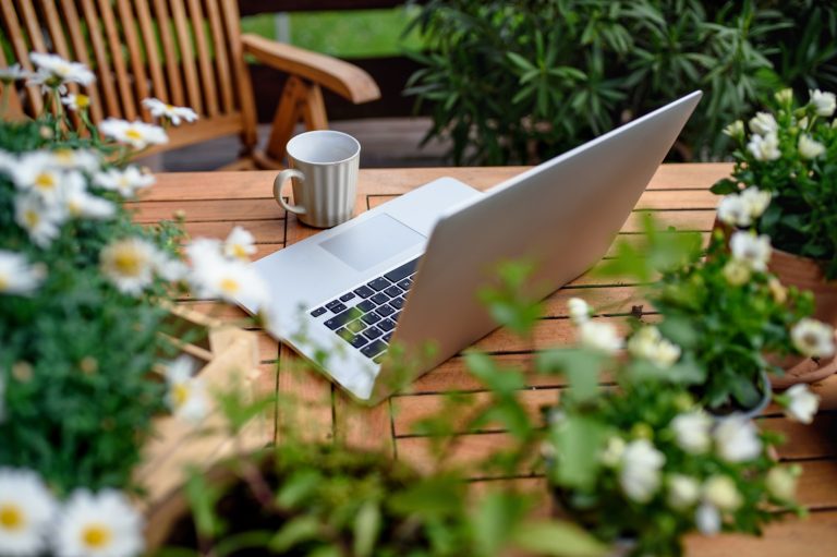 Top view of laptop on table on balcony in summer, outdoors office concept