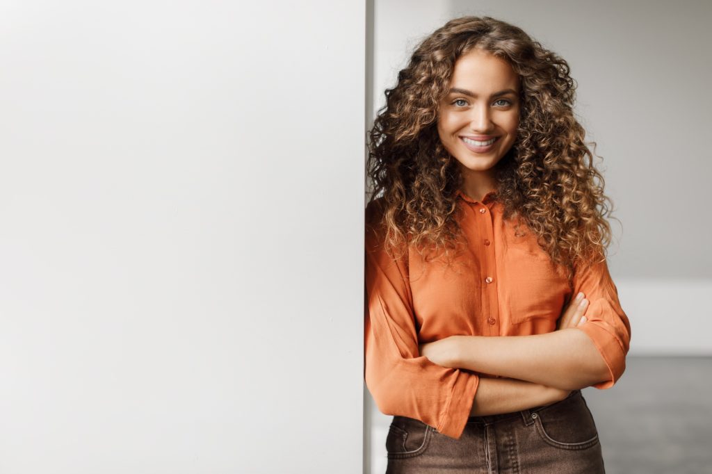 Confident businesswoman with arms crossed near blank board